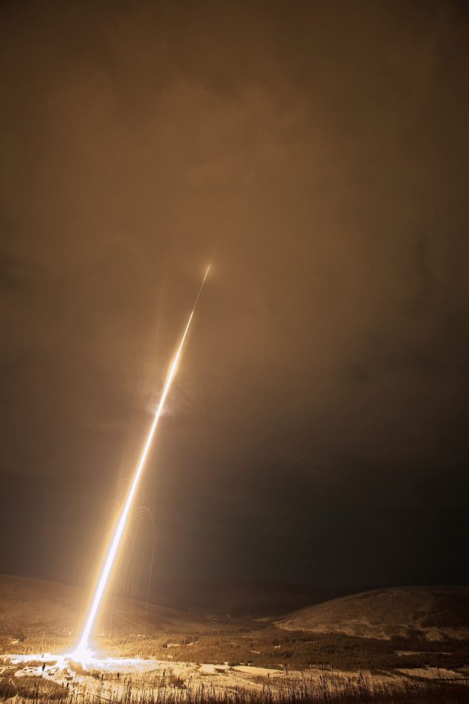 A rocket lifting off into the night sky on a column of flame